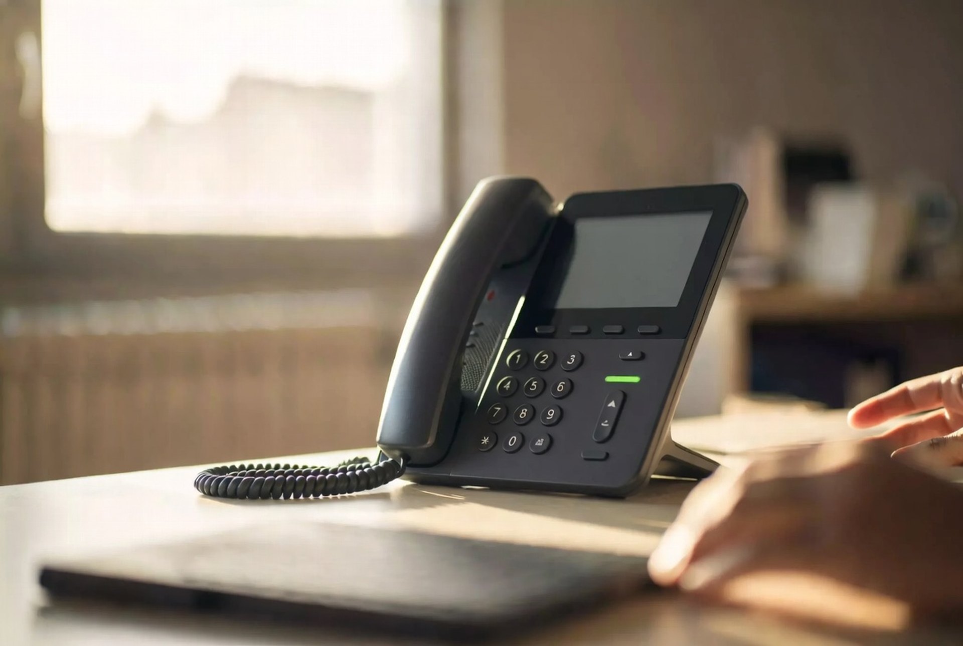 An IP desk phone ready on a clean desk in warm light