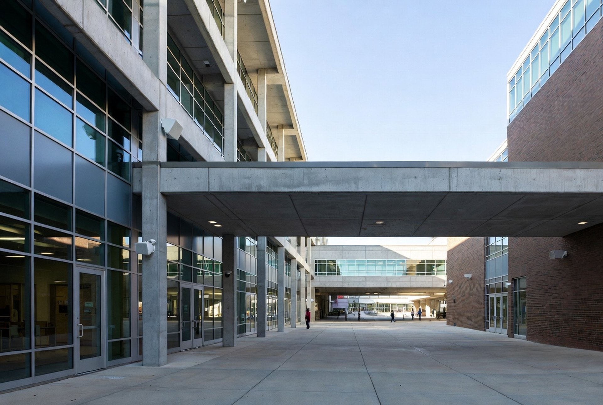 A modern community college commons with glass academic buildings and a covered walkway