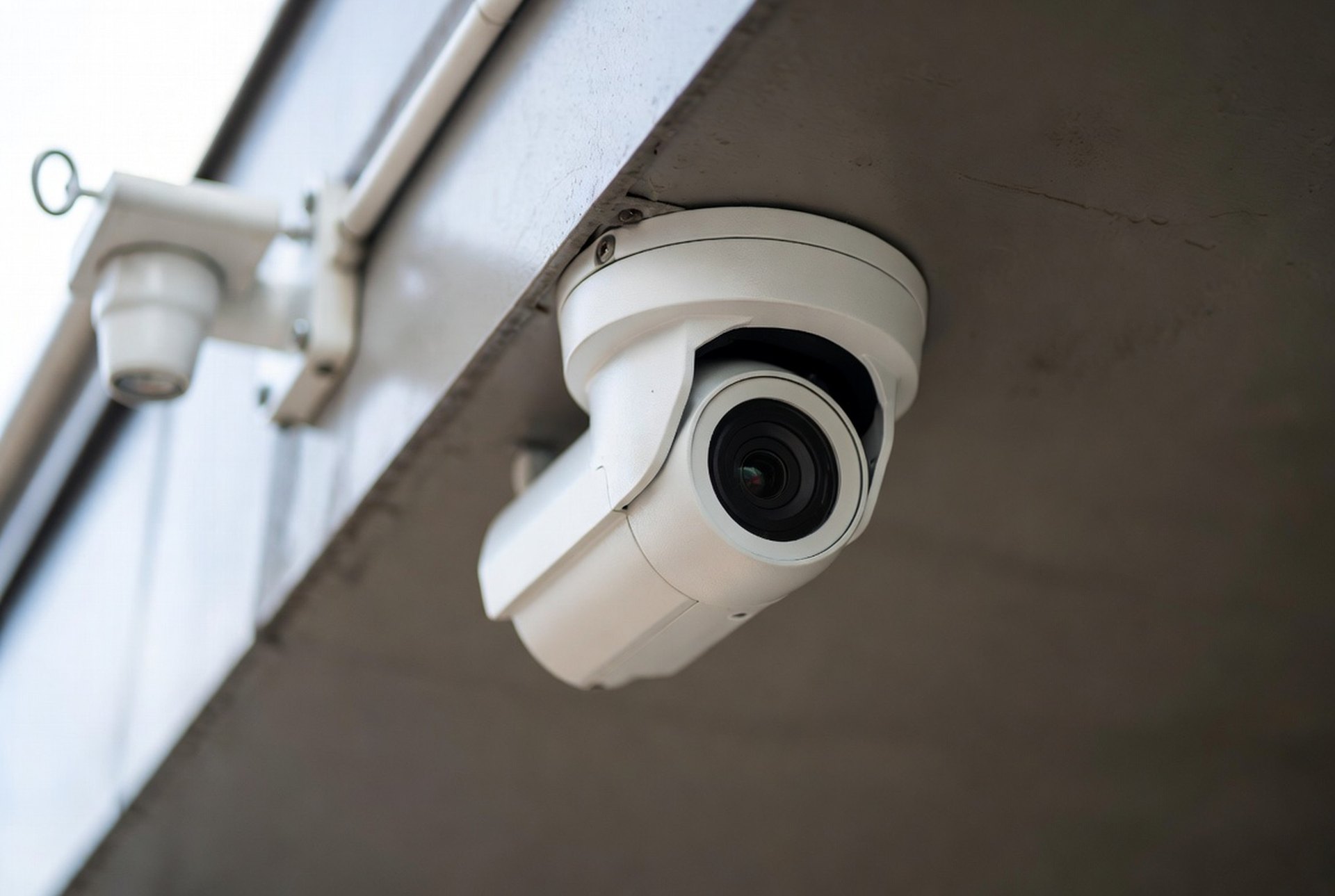 A modern IP dome security camera mounted at a building entrance